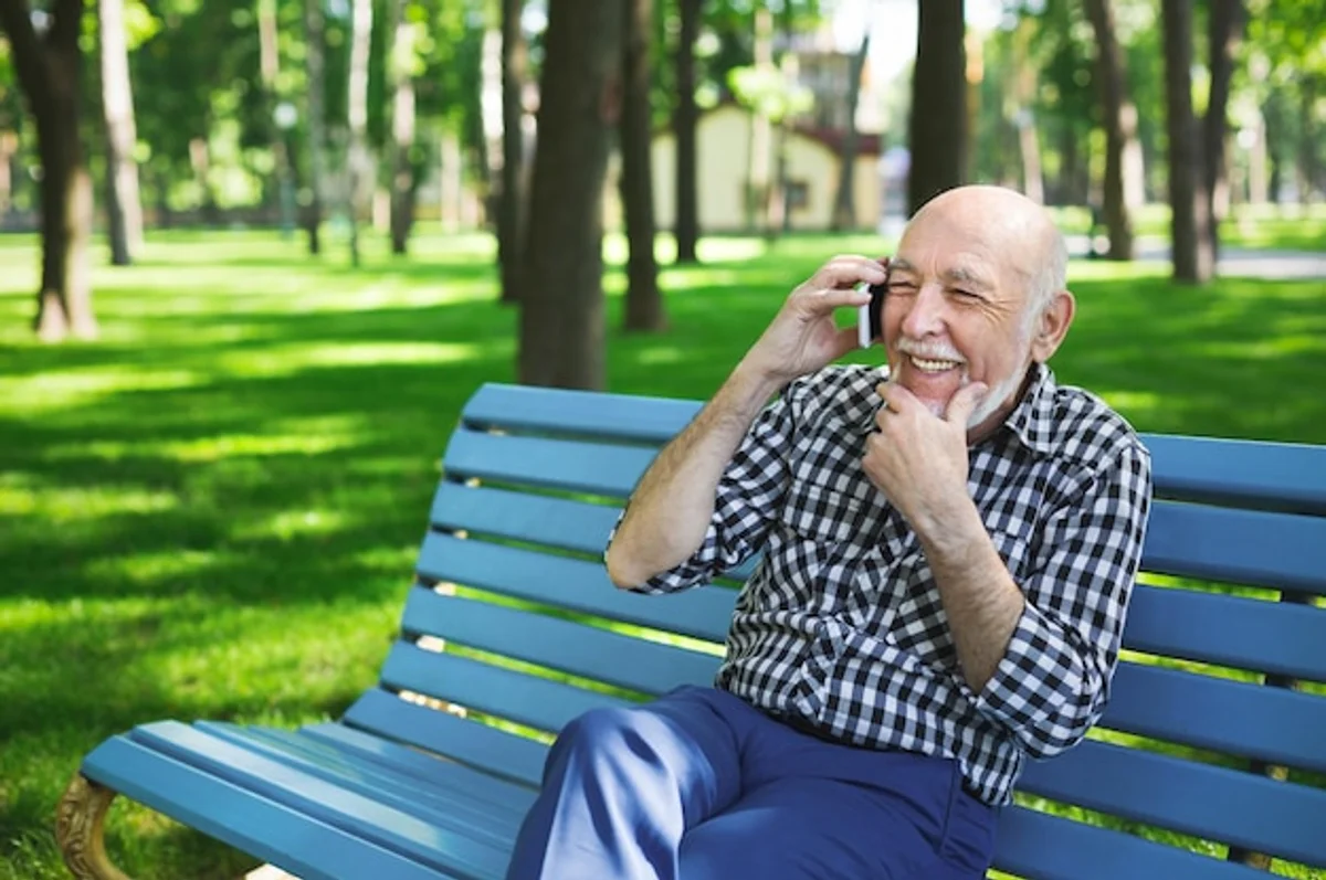 senior using smartphone outdoors in summer shade