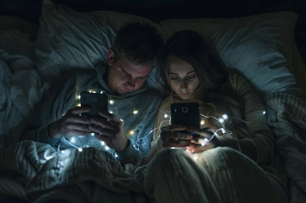 couple in bed both on smartphones looking distant