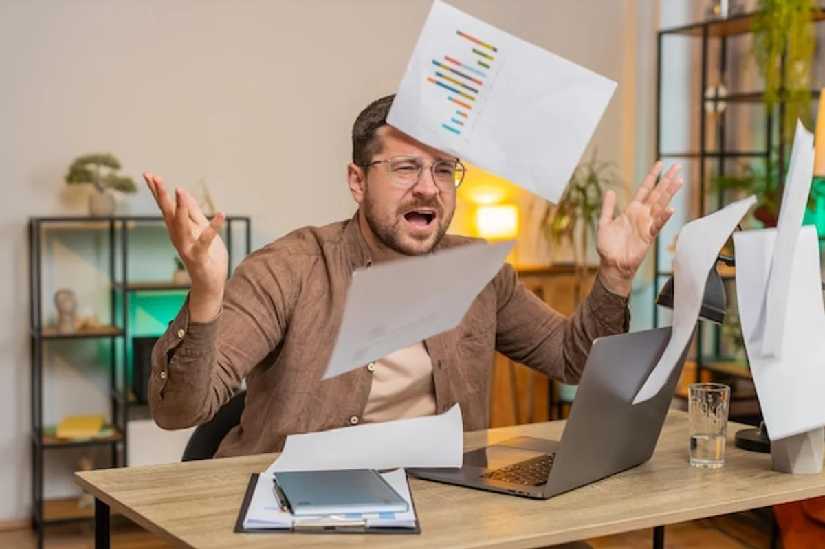 man checking bills at home table paperwork stress