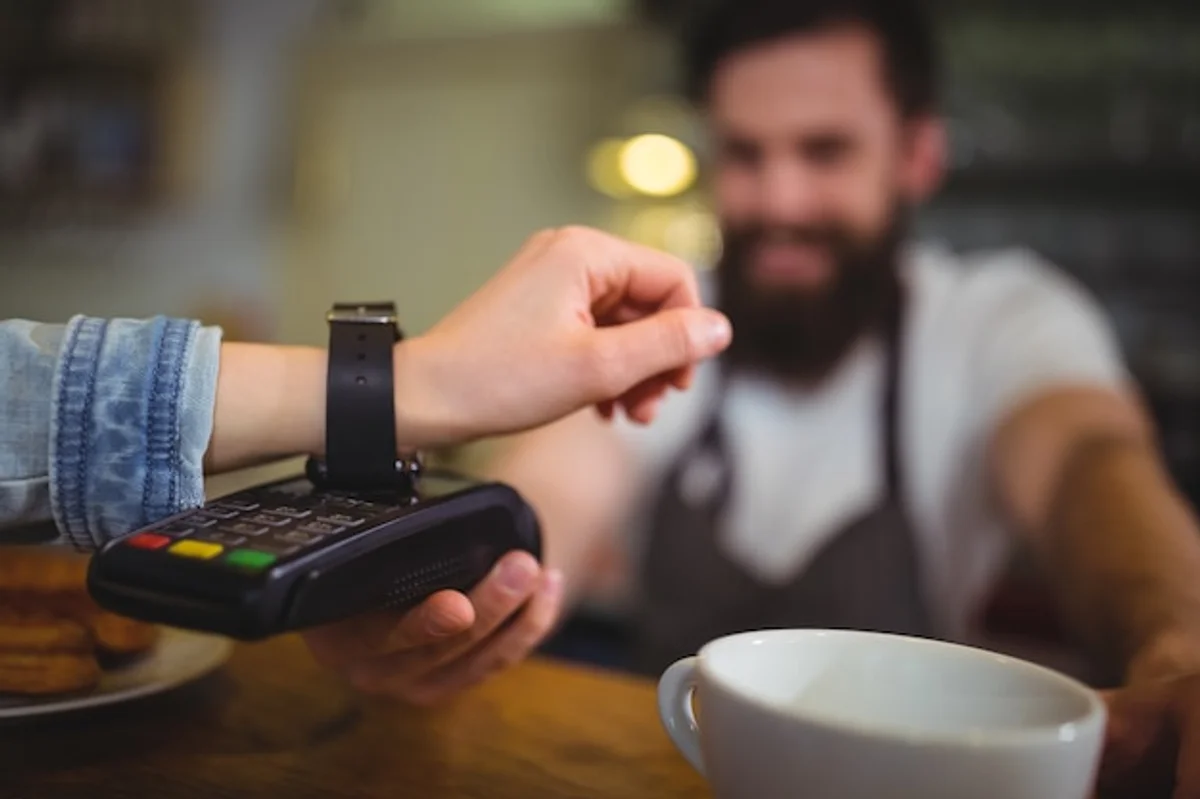 lifestyle woman using smartwatch for payments at cafe