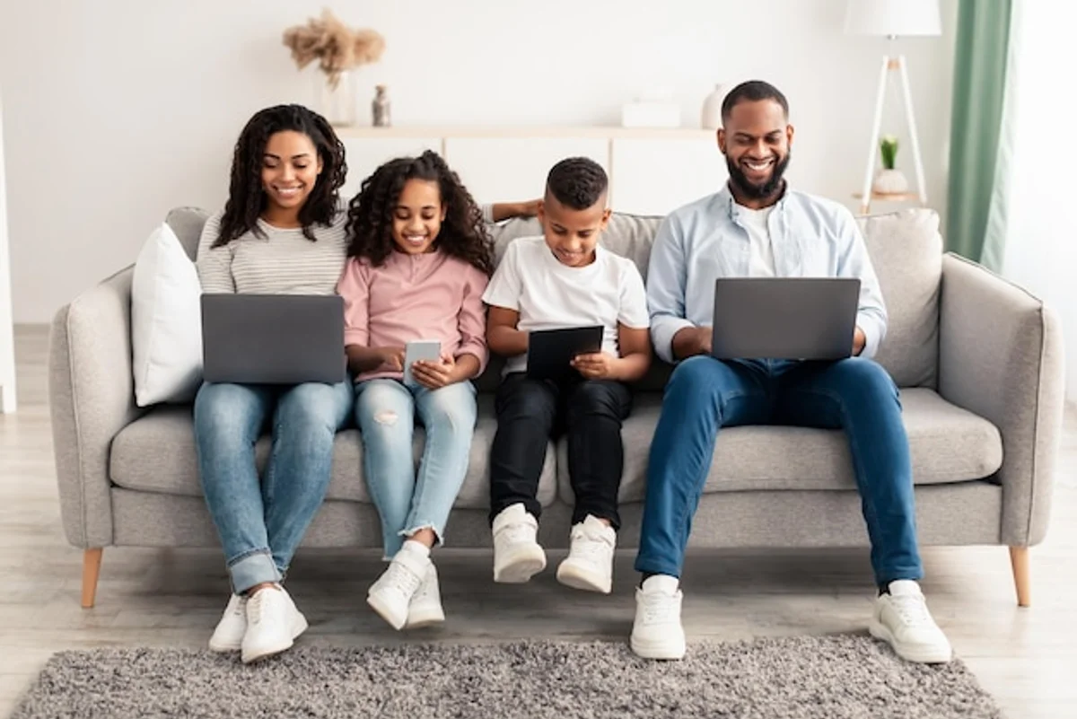 family using WiFi devices smiling on couch modern home
