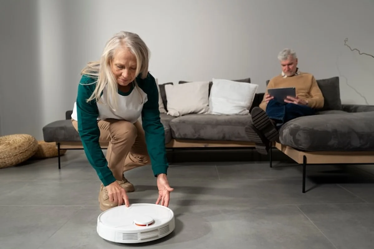 elderly couple using robot vacuum in living room