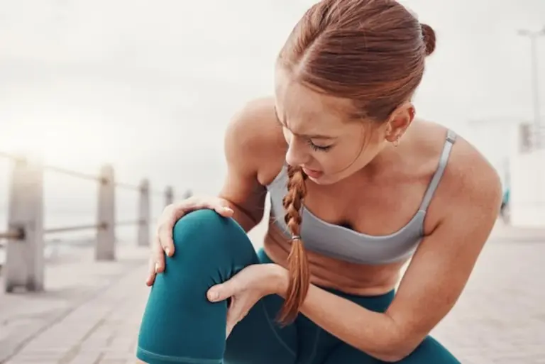 injured athlete holding leg stretching gym