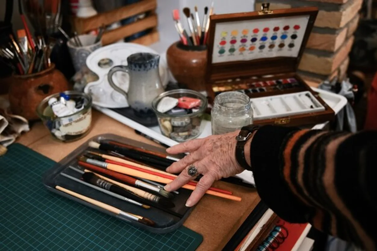 elderly hands painting with watercolor on table