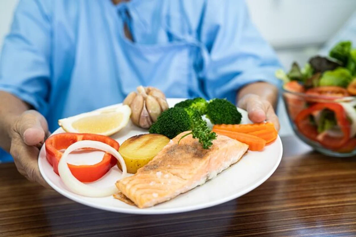 senior woman cooking healthy meal with fresh vegetables and salmon