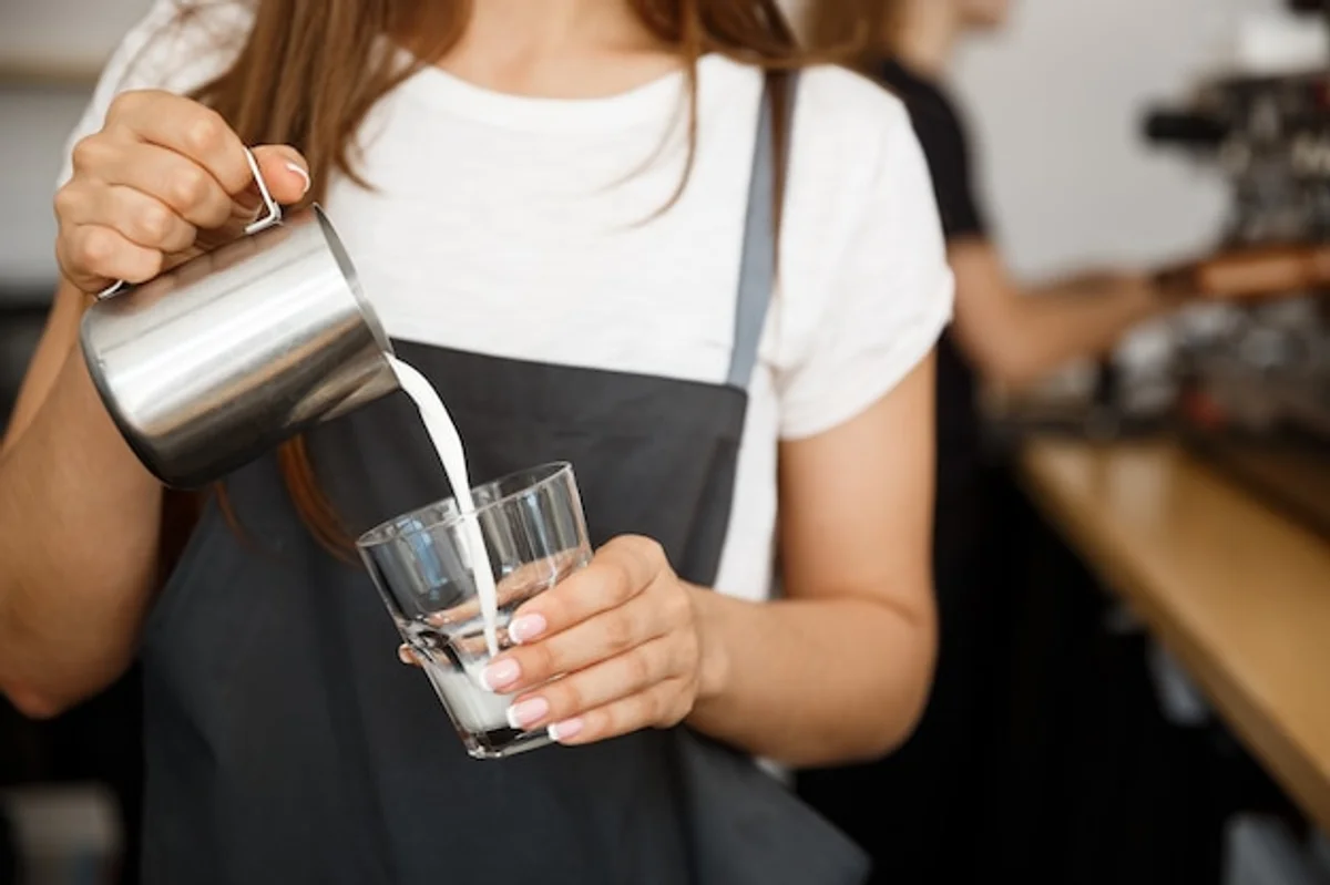 barista pouring vegan oat milk into coffee cappuccino