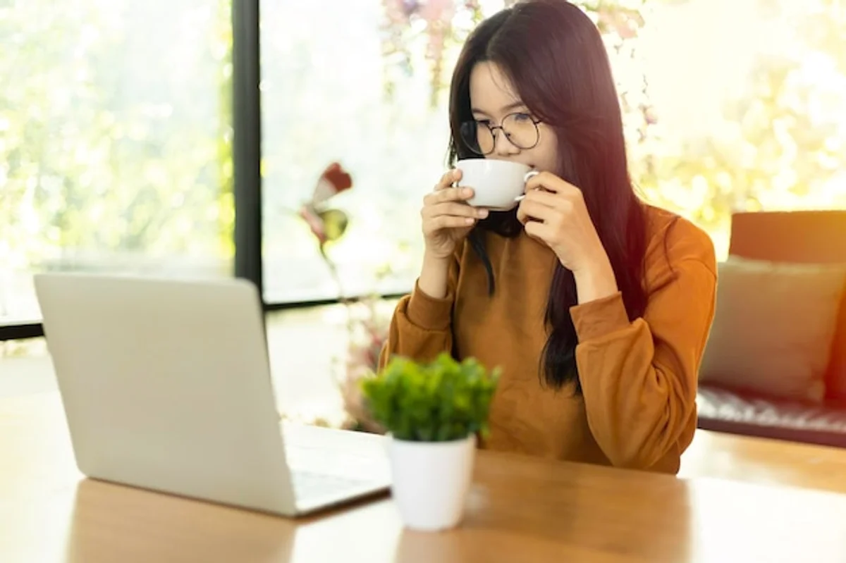 happy person drinking coffee at work desk daylight