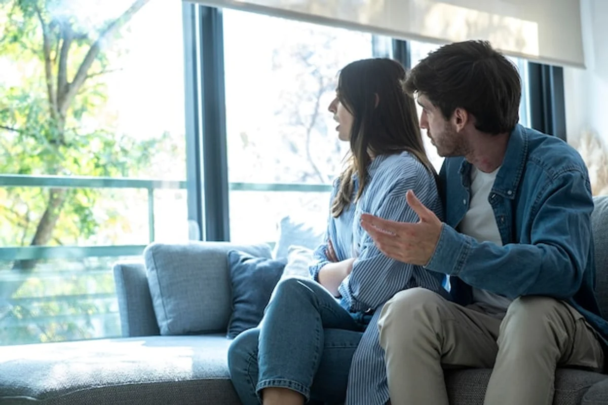 couple talking on a couch with serious expressions