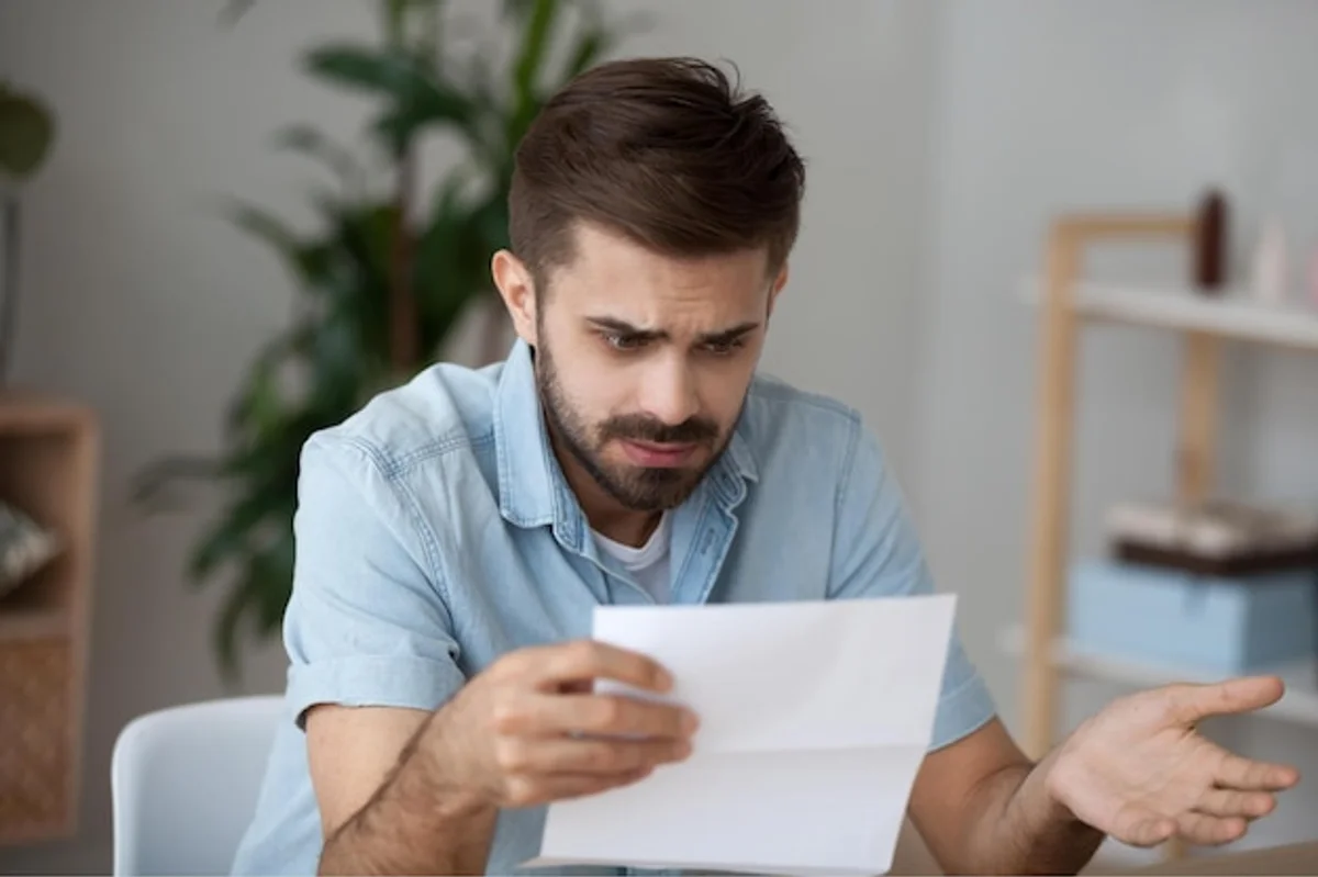 man frustrated looking at receipts at home