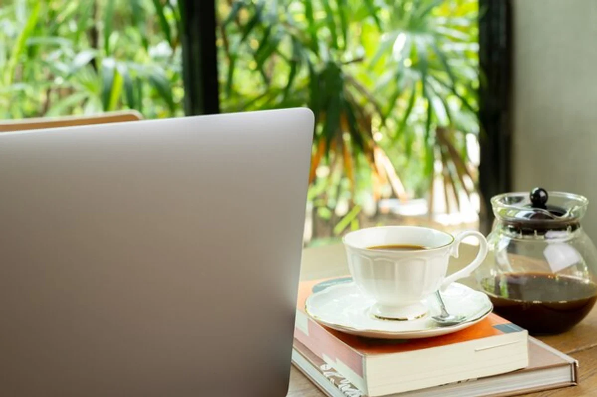 modern mug of freshly brewed green tea with laptop nearby